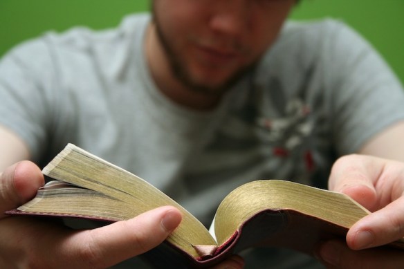 Young man reading small Bible